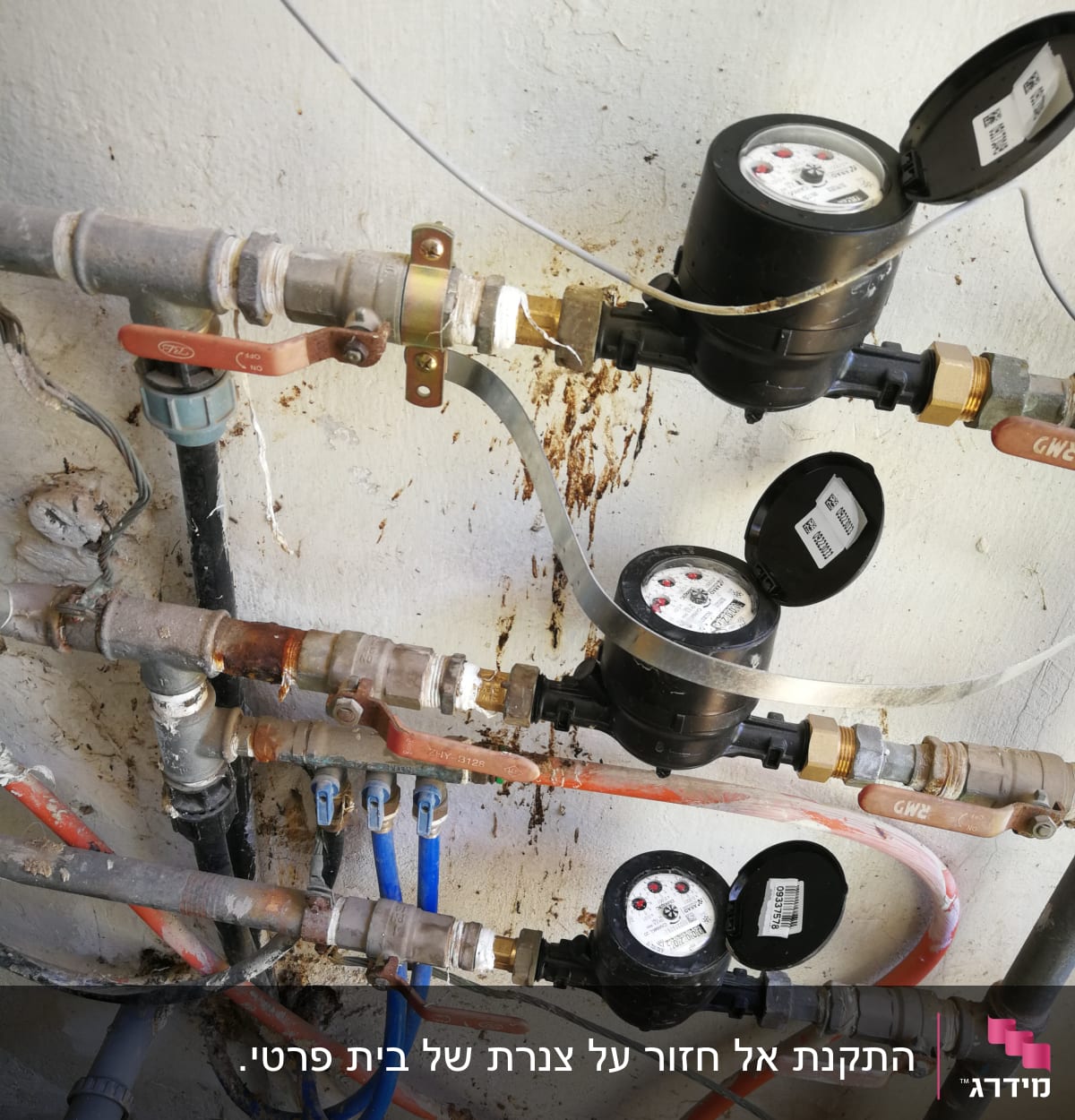 מד מים עם צינורות וברזים מחוברים לקיר